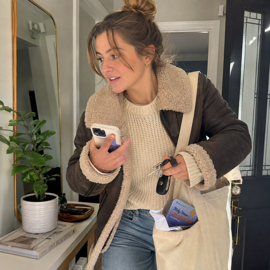 A woman rushing to get ready in soft daylight, keys and phone in hand, no time to sit down for breakfast.