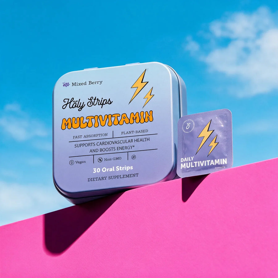 Holy Strips Mixed Berry Multivitamin tin and individual purple strip packet on a pink ledge against a blue sky.