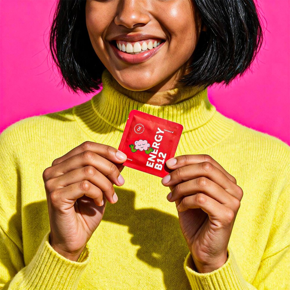 Woman holding a red Energy B12 dissolvable vitamin strip sachet